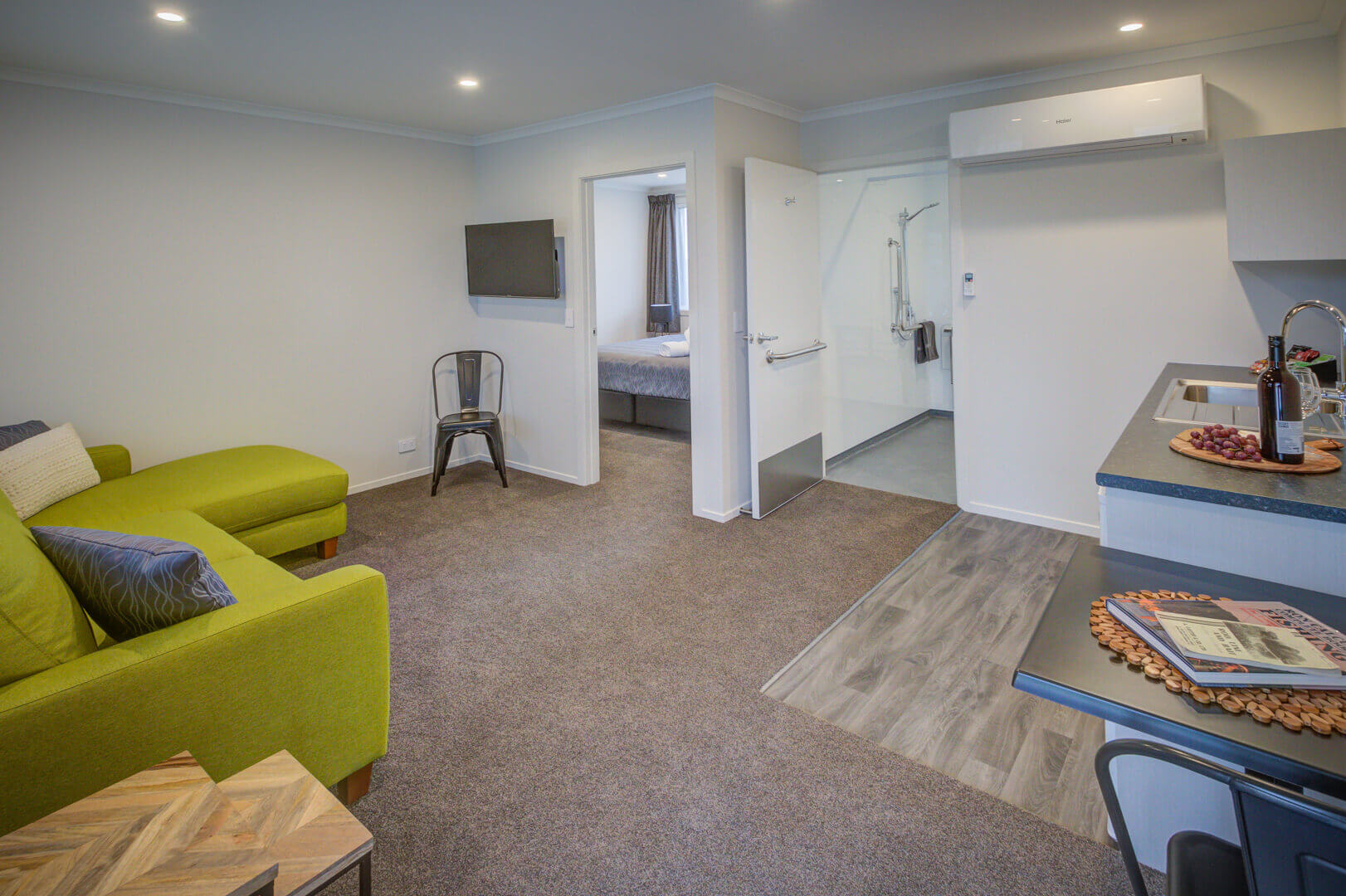 Interior of spacious, accessible motel suite with view to bedroom and bathroom from the living area.