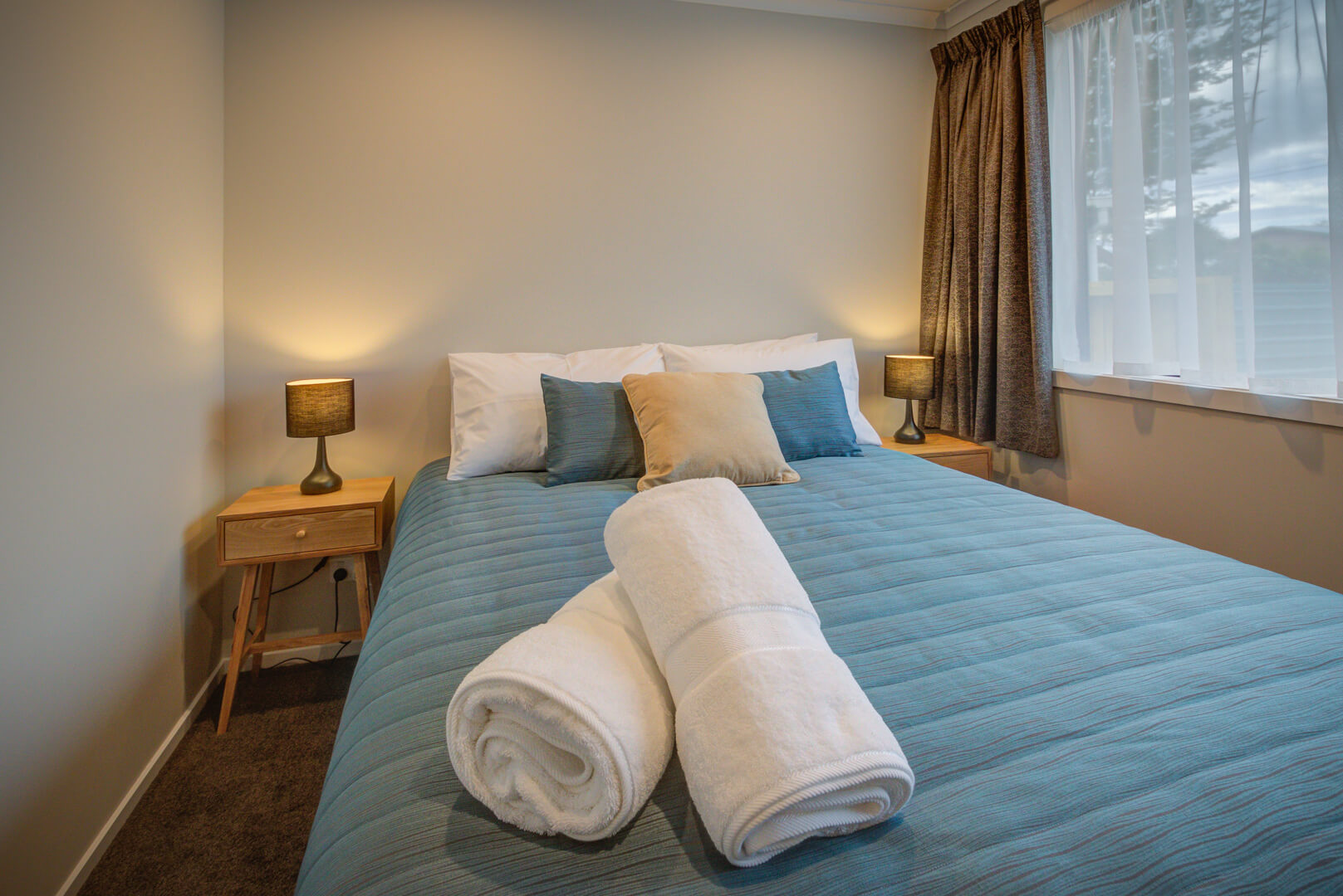 Queen sized bed with blue bedspread in one-bedroom unit at Dusky Motels, Te Anau