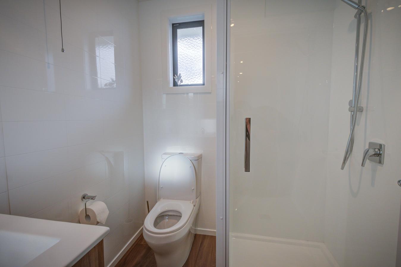 Bathroom with toilet, handbasin and shower at Dusky Motels.