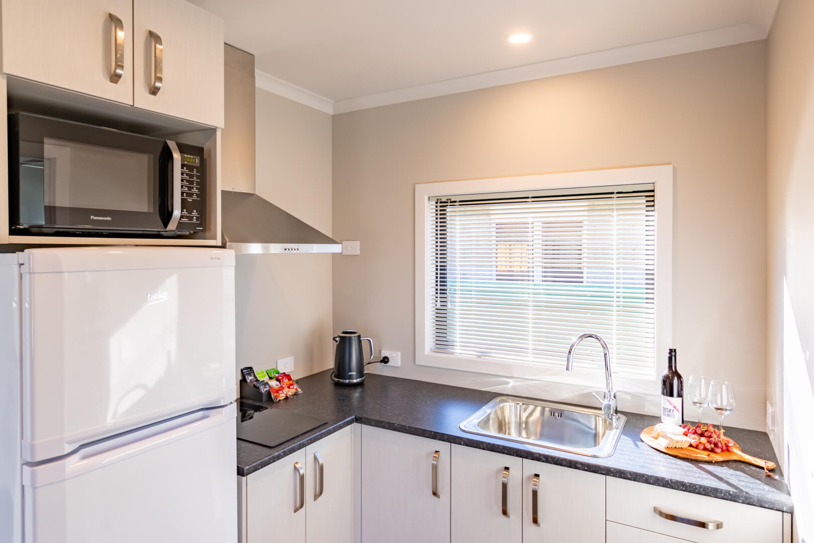 Modern kitchen with fridge, microwave and cooktop in the Dusky Motels two-bedroom suite.